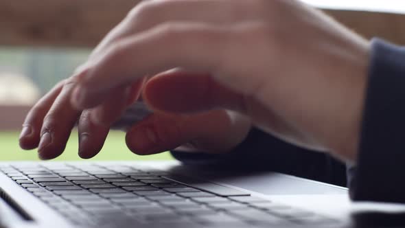the Hands of a Young Man are Typing on a Laptop Sitting on the Terrace Against the Backdrop of a alt