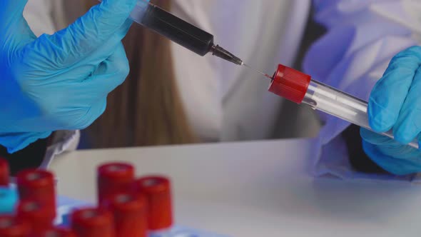 Doctor Pours Blood From a Syringe to Test Tube Close Up alt