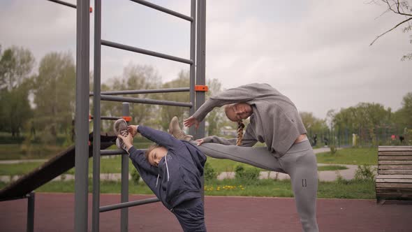  Mother and Daughter Doing Exercises on Open Air Sport Playground alt