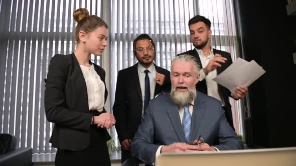 People of different nationalities and ages discuss work with their supervisor alt