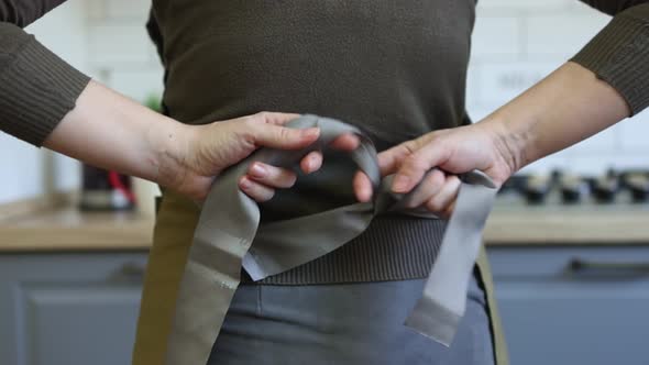 Closeup Caucasian Hands Tying Up Brown Apron Strings Behind Back Preparing Cook alt