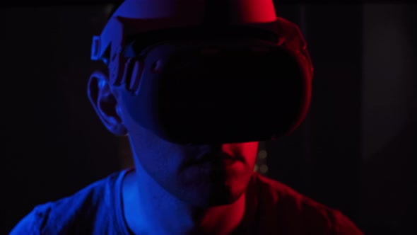Young Man Plays a Game in a VR Helmet Under RedBlue Light alt