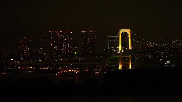 Late night scene of rainbow bridge with buildings of Tokyo city in background