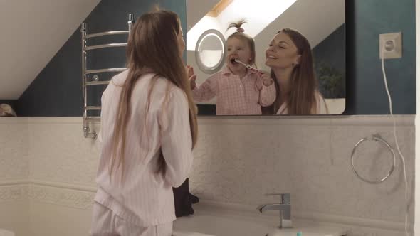 Lovely Mother with Little Family Brushing Teeth in Bathroom