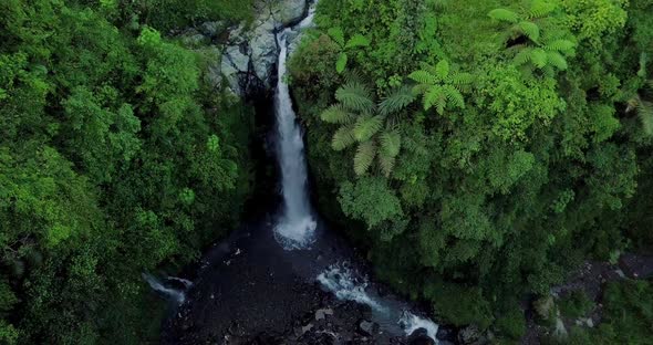 Aerial view from drone flying over nature view a river that ends in a waterfall with surrounding veg alt