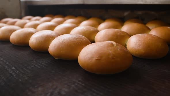 Bread Comes Out of the Oven in Closeup on a Conveyor Belt and is Sprayed with Water to Add Gloss and