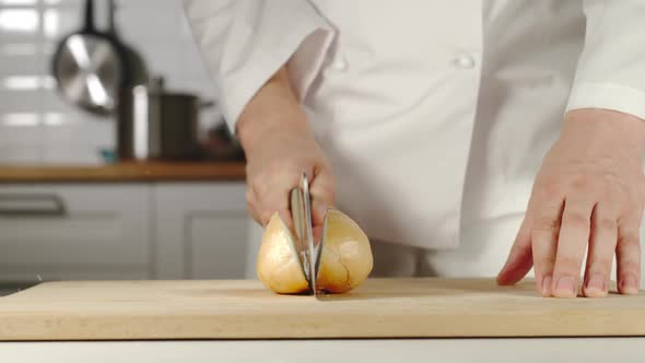 Chef Chopping A Head Of Onion On Wooden Board While Cooking
