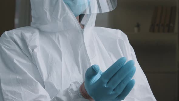 Unrecognizable Woman Doctor Medical Worker Wears Special Protective Suit Uniform Puts on Rubber alt