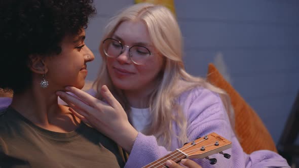 A Young LGBT Couple Lies in Bed and Plays the Ukulele Kissing and Smiling