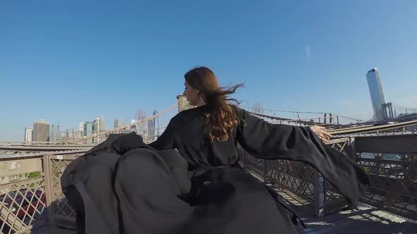 Woman in Black Long Flowing Dress Walks Across the Brooklyn Bridge in New York
