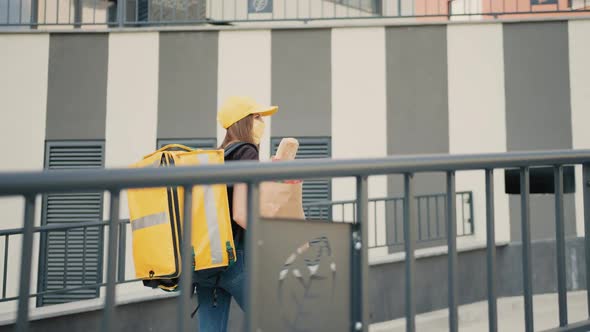 Caucasian Young Pretty Woman Delivery Worker Cap and Medical Mask Walking the alt