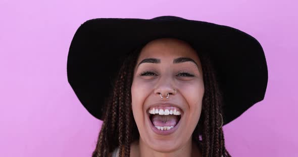 Young african woman with braids laughing on camera while wearing trendy hat alt