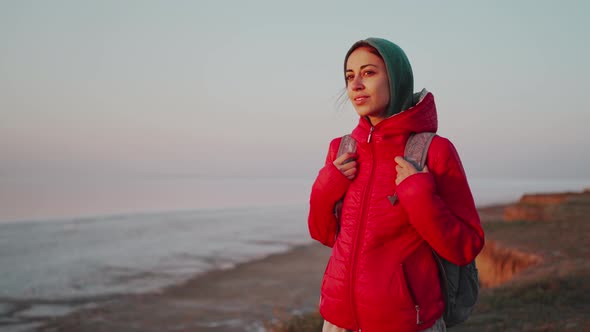 Young Woman Traveler with Backpack Meeting Sunrise at Deserted Sea Beach