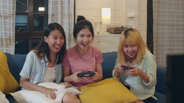 Female using joystick having funny moment together on sofa in living room in night. alt