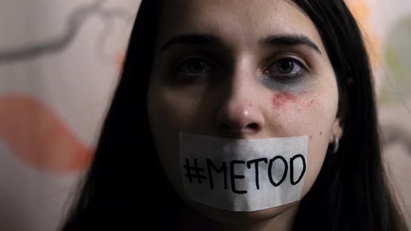 A young female victim of violence raises her head and shows the word "metoo" on her face