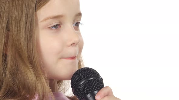 Little Girl Sings the Song Into the Microphone. White Background. Close Up alt