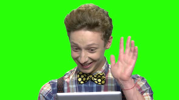 Teen Boy in Fashionable Clothes Talking with Someone Using Tablet alt