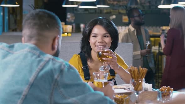 Cheerful Latin American woman sitting in bar with man