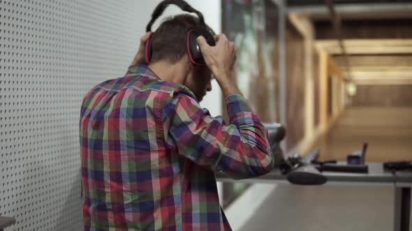 Rare View of a Man in Indoors Shooting Range Putting on Protective Headphones alt