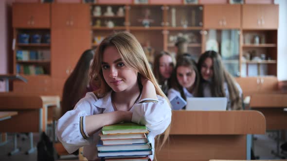 A Student Poses with Textbooks at Her Desk in Her Class alt