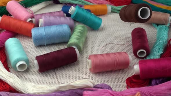 Falling multicolored spools on burlap against the background of colorful mouline threads alt