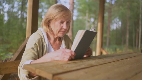 Elderly Senior Woman with Poor Eyesight Trying to Read a Book Without Prescription Glasses on a