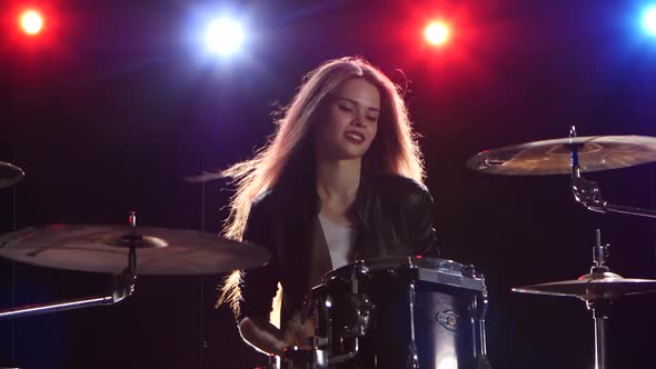 Girl Is Playing the Drums. Black Background. Red Blue Light From Behind alt