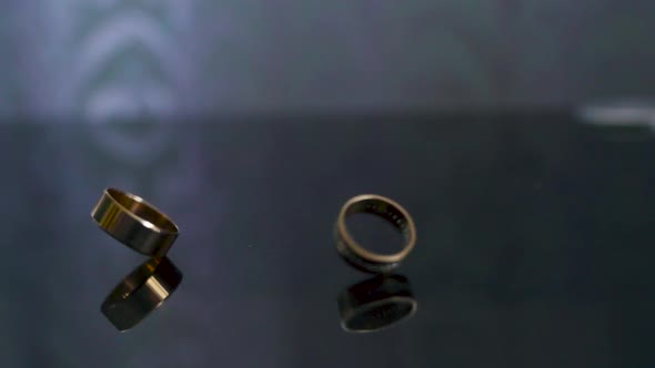 Rotating two wedding rings. Rings rotates in slow motion on the mirror table alt