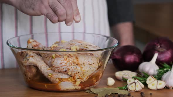 Salt the Raw chicken legs for frying in glass bowl with marinade alt