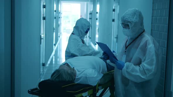 Two Doctors Treat a Patient on Stretcher During Coornavirus Pandemic. alt