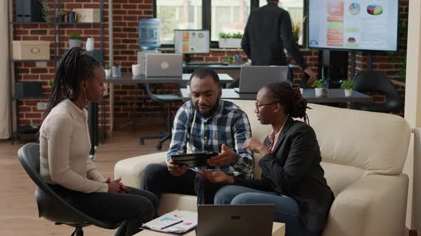 Office Workers Looking at Financial Statistics on Digital Tablet alt