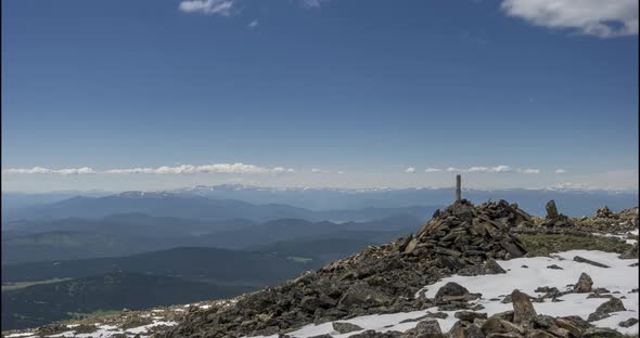 Time Lapse of Cloudscape Behind of the Mountains Top. Snow, Rocks, Cliffs and Deep Blue Sky. High alt