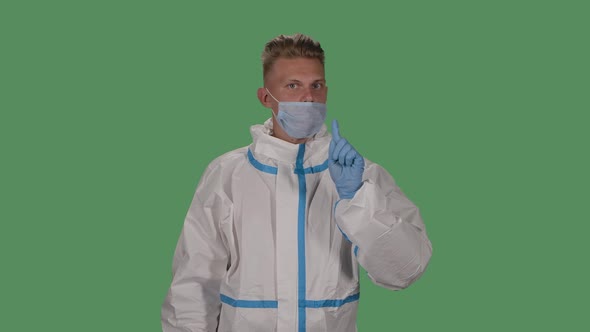 Portrait of a Man in a Protective Suit and Medical Mask Looks Into the Camera and Shows How To alt
