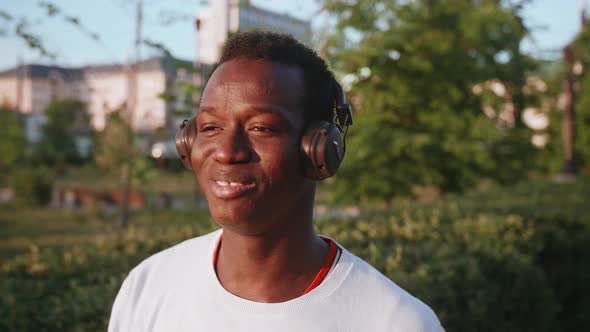 Black Young Man Listens to Music with Headphones