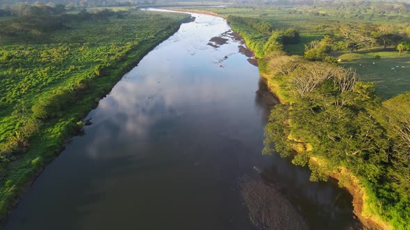 Drone flying over a river towards the horizon alt
