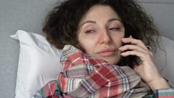 Portrait of a Sick Woman with Flu Cold or Coronavirus Symptoms Talking on a Cell Phone alt