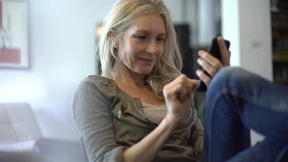 Mature woman texting on her smart phone at home