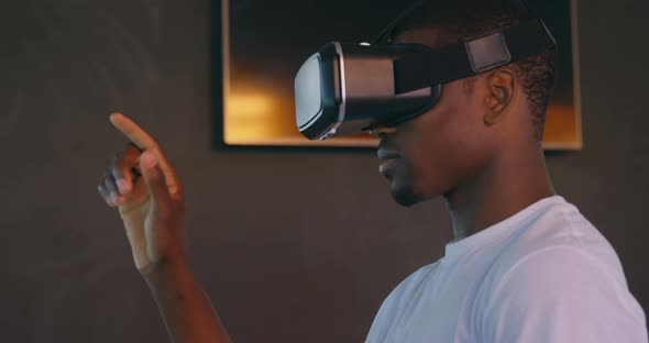 Side view of young black male executive using virtual reality headset at desk in modern office 4k alt