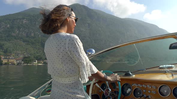 A woman on a classic luxury wooden runabout boat on an Italian lake alt