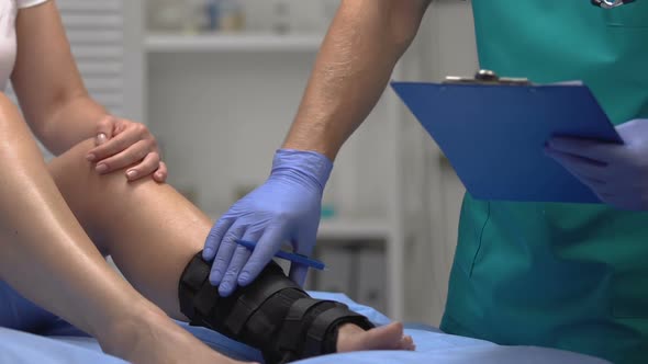 Doctor Checking Patient Leg in Ankle Wrap, Recording Examination Result, Health