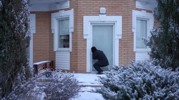 Wide Shot Suspicious Man in Black Clothing Looking Inside House Through Windows Checking Empty Home alt