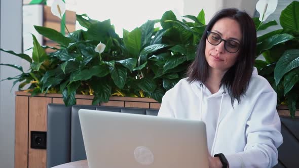 Portrait of a Young Caucasian Female Freelancer Using a Laptop to Work at a Distance Sitting in a alt