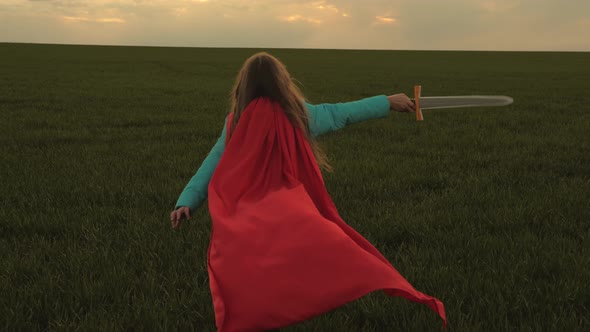 Child Play Knights. Girl in a Red Cloak Runs with Swords in His Hand Across Field Playing Medieval