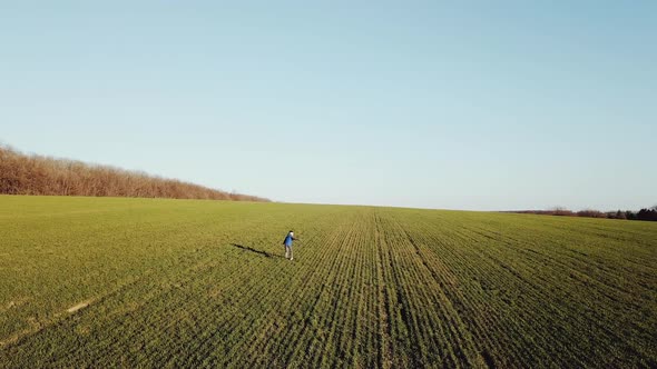 Cute boy is running around the green field in the early spring. Active kid chasing happily alt