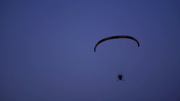 The Pilot on a Paraglider Flies From the Camera Gradually Moving Away Into the Distance Against the alt