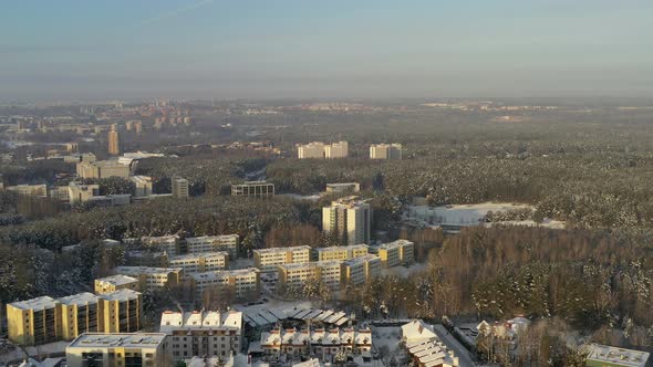 AERIAL: Buildings in Forest on a Cold Bright Warm Looking Day in Winter
