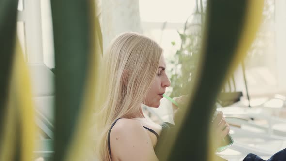 Profile View of Blonde Woman Drinking Soft Drink From a Straw