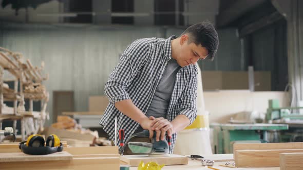 Handsome Woodworker Using Polishing Machine To Polish Wood in Workshop alt
