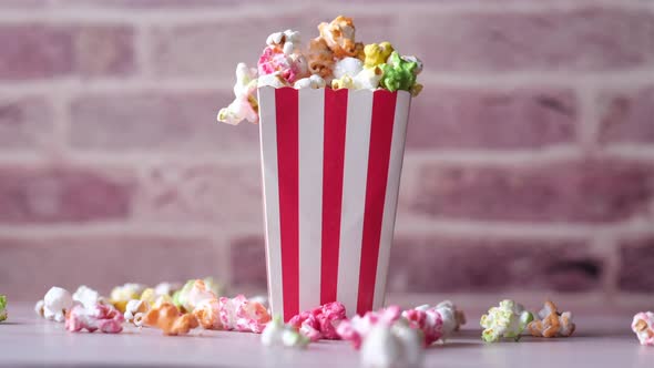 Popcorn Spilling From a Paper Container on Wooden Background alt