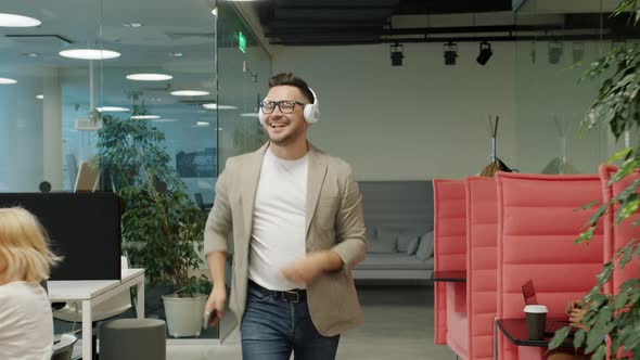 Joyful Man in Headphones Dancing in Office Doing High-five with Coworker Having Fun alt